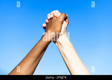 Le mani multietniche delle donne insieme contro il cielo blu. Foto Stock