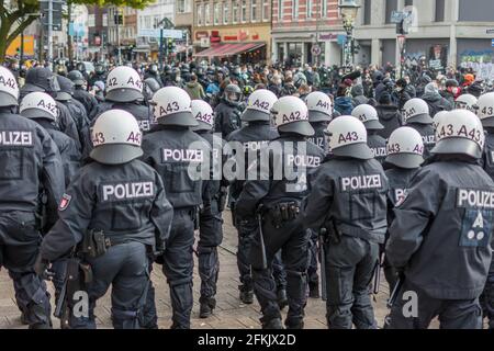 Amburgo, Germania - 1 maggio 2021: Polizia tedesca di rivolta al fianco di una manifestazione con caschi durante. Manifestanti in background il giorno di maggio Foto Stock