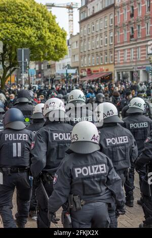 Amburgo, Germania - 1 maggio 2021: Polizia tedesca di rivolta al fianco di una manifestazione con caschi durante. Manifestanti in background il giorno di maggio Foto Stock