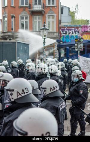 Amburgo, Germania - 1 maggio 2021: Polizia antisommossa al fianco di una manifestazione con caschi durante. Manifestanti in background il giorno di maggio, Festa del lavoro Foto Stock