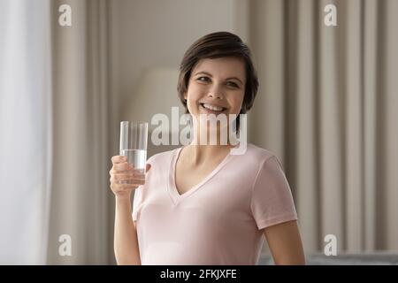 Donna incinta sorridente beve acqua minerale pulita Foto Stock