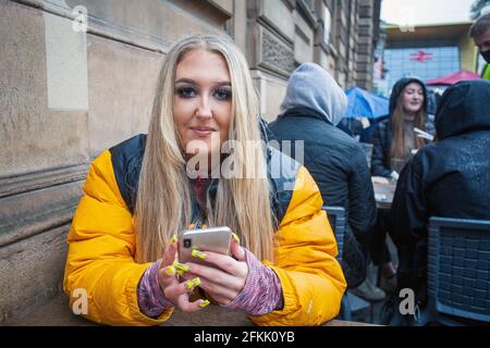 Giovane donna con chiodi lunghi acrilici curati con telefono cellulare a Glasgow, Scozia Foto Stock