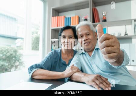 Coppia asiatica senior che utilizza la calcolatrice e la documentazione sulla scrivania a casa per calcolare le spese e il reddito. E risparmio dopo il pensionamento. Concetto di fina Foto Stock