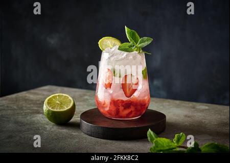 Limonata fresca fatta in casa con fragole, lime e menta su sfondo ligneo. Bevanda sana estiva Foto Stock