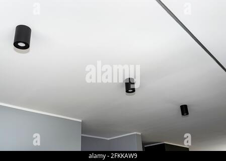 Moderna illuminazione a LED a forma di tubo, rivestita di vernice nera opaca, sospesa al soffitto. Foto Stock