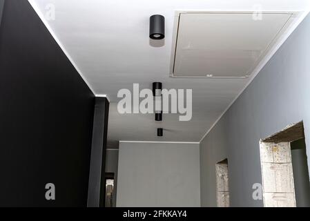 Moderna illuminazione a LED a forma di tubo, rivestita di vernice nera opaca, sospesa al soffitto. Foto Stock