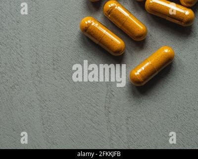 capsule turmeriche gialle su sfondo grigio di legno Foto Stock