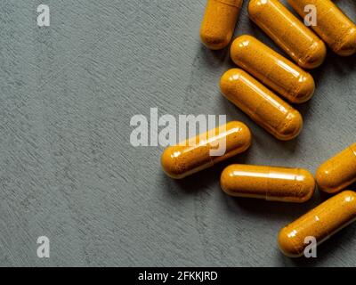 capsule curcuma su fondo grigio di legno con spazio per la copia Foto Stock