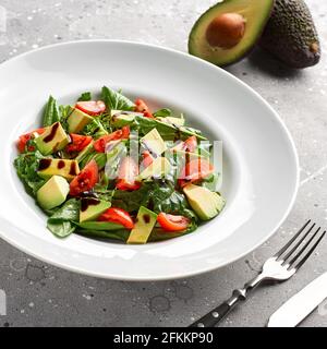 Insalata estiva fresca con avocado, lattuga, pomodoro e semi di lino su sfondo grigio.Close up, concetto di alimentazione sana. Foto Stock