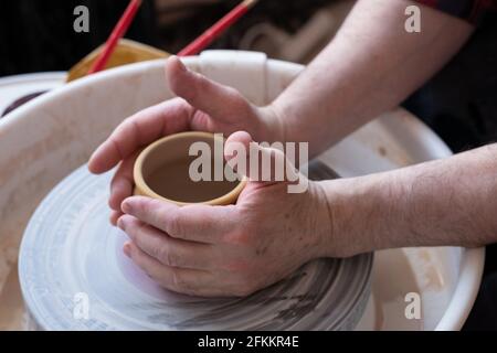 Ruota di vasaio e mani di artigiano che fanno una caraffa Foto Stock