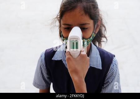 Una studentessa indiana che ottiene un controllo di temperatura prima di andare a. Scuola durante la pandemia COVID-19 Foto Stock