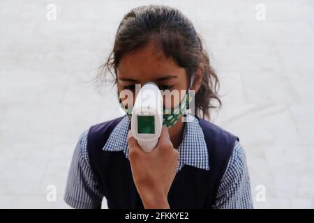 Una studentessa indiana che ottiene un controllo di temperatura prima di andare a. Scuola durante la pandemia COVID-19 Foto Stock