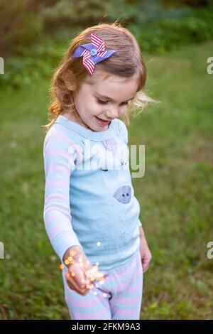 Ragazza che tiene Sparkler con il 4 luglio pin Foto Stock