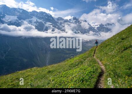 Escursionista su un sentiero, nel retro Breithorn e Tschingelhorn, Alpi Bernesi, Oberland Bernese, Lauterbrunnen, Svizzera Foto Stock