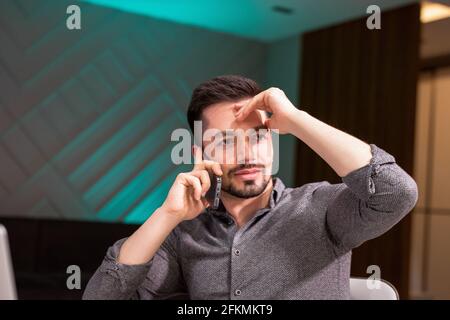 giovane uomo bruna bearded lavora su progetto di affari nel suo ufficio moderno, lookis concentrato prendendo appunti al suo ordine del giorno. Foto Stock