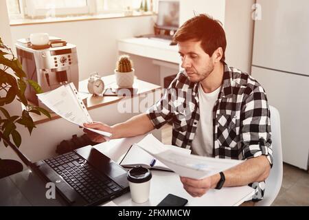 Uomo che lavora in ufficio a casa con computer portatile e smartphone. Concetto di business online. Lavoro remoto Foto Stock