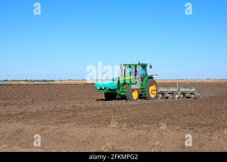 Trattore John Deere 8120 che arano un campo di cotone vicino a Narrabri, NSW, Australia. Sulla parte anteriore del trattore è presente un serbatoio fertilizzante liquido. Foto Stock