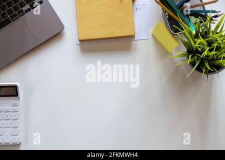 Tavolo da lavoro bianco con computer portatile a schermo vuoto, notebook, mouse, tazza di caffè e altro ufficio. Vista dall'alto con spazio per la copia. Foto Stock