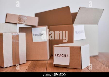 Varie scatole di cartone con etichetta fragile su tavolo di legno Foto Stock