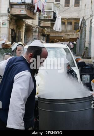 Un ebreo Haredi immergere utensili da cucina in acqua bollente in un processo chiamato Hagalat Kelim. MEA She'arim , Gerusalemme, Israele. Foto Stock