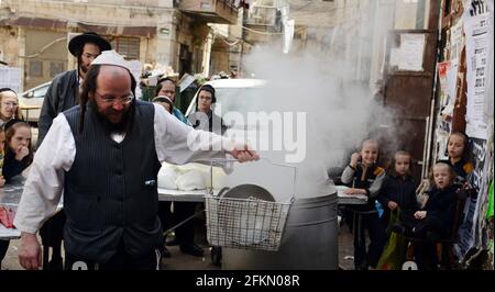 Un ebreo Haredi immergere utensili da cucina in acqua bollente in un processo chiamato Hagalat Kelim. MEA She'arim , Gerusalemme, Israele. Foto Stock