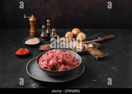 Forcemeat crudo macinato di manzo in una ciotola su sfondo scuro Foto Stock