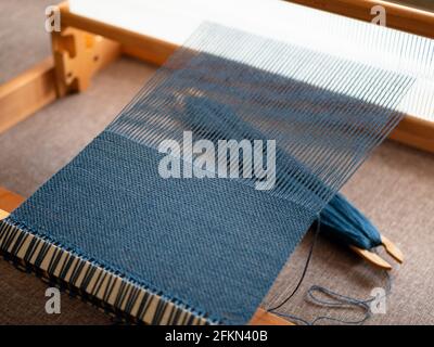 Creazione del tessuto usando un telaio di tessitura Foto Stock