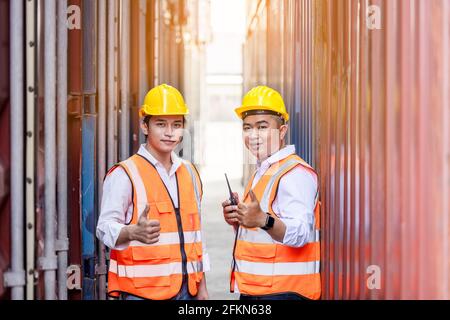 Due operai o ingegneri che cercano e puntano qualcosa dentro magazzino dei contenitori Foto Stock