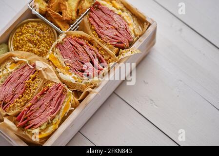 Enormi panini con pastrami di manzo in scatola di legno. Servito con patate al forno, sottaceti Foto Stock