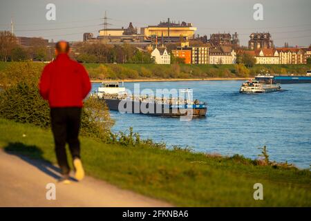 Joggers sulla diga del Reno, navi da carico sul Reno vicino Duisburg-Laar, case sulla strada della diga, scenario industriale del ArcelorMittal Hochfeld GMB Foto Stock