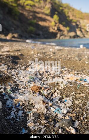 Piccole parti in plastica e microplastica sulla spiaggia di sabbia Foto Stock