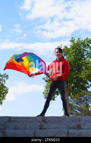 Una ragazza transgender con la bandiera gay. Persone autentiche non binarie. Giornata dell'orgoglio gay Foto Stock