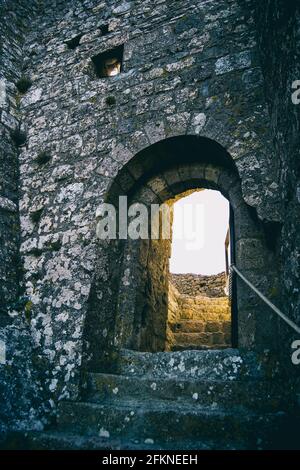 vecchie scale di pietra che conducono ad un muro di pietra con un arco come porta Foto Stock