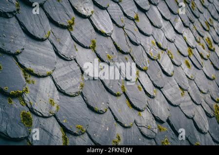 tetto con vecchie piastrelle di colore scuro, tra nero e grigio. Creare una ripetizione con texture da una prospettiva angolata Foto Stock