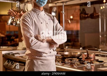 Chef orgoglioso in piedi con braccia incrociate in cucina Foto Stock