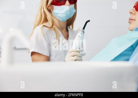 Medico in maschera portando luce di cura dentale alla bocca del capretto Foto Stock