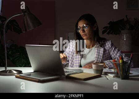 Fidata giovane indiana mista-razza Businesswoman che lavora in ufficio a notte. Ragazza che lavora fuori orario Foto Stock