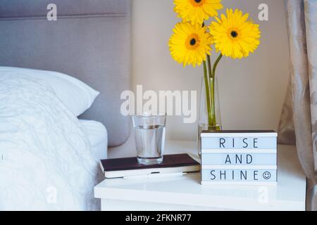 Buon concetto di mattina. Inspiration Motivational Life indica il messaggio "Rise and Shine" su un lightbox con notebook e un bicchiere d'acqua e fresco sole Foto Stock