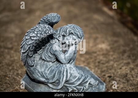 Fuoco vicino e selettivo di una statuetta dell'angelo in a. cortile posteriore privato con profondità di campo intenzionale poco profonda e. bokeh Foto Stock