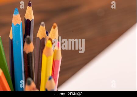 Matite colorate e fogli bianchi di carta su un tavolo di legno. Messa a fuoco selettiva in primo piano. Foto Stock