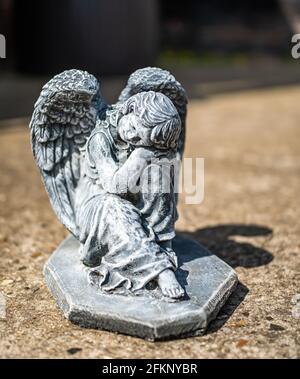 Fuoco vicino e selettivo di una statuetta dell'angelo in a. cortile posteriore privato con profondità di campo intenzionale poco profonda e. bokeh Foto Stock