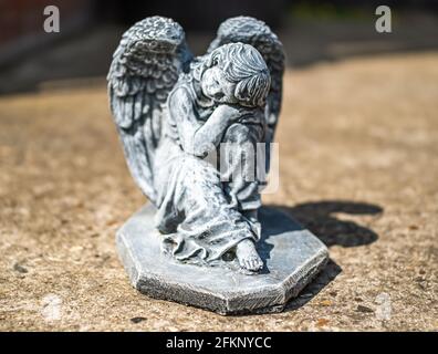 Fuoco vicino e selettivo di una statuetta dell'angelo in a. cortile posteriore privato con profondità di campo intenzionale poco profonda e. bokeh Foto Stock