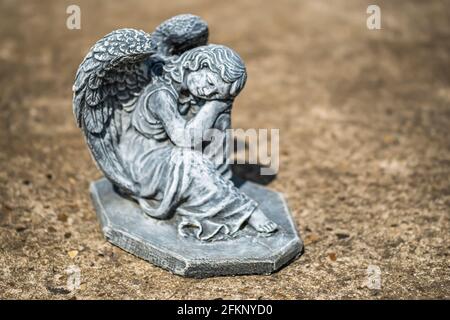 Fuoco vicino e selettivo di una statuetta dell'angelo in a. cortile posteriore privato con profondità di campo intenzionale poco profonda e. bokeh Foto Stock