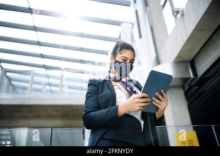 Giovane hostess aria con tablet in aeroporto lounge, coronavirus, viaggi e nuovo normale. Foto Stock
