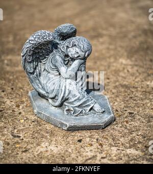 Fuoco vicino e selettivo di una statuetta dell'angelo in a. cortile posteriore privato con profondità di campo intenzionale poco profonda e. bokeh Foto Stock