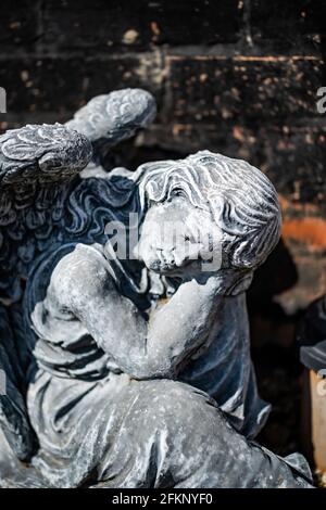 Fuoco vicino e selettivo di una statuetta dell'angelo in a. cortile posteriore privato con profondità di campo intenzionale poco profonda e. bokeh Foto Stock