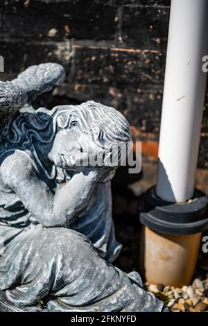 Fuoco vicino e selettivo di una statuetta dell'angelo in a. cortile posteriore privato con profondità di campo intenzionale poco profonda e. bokeh Foto Stock