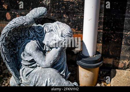 Fuoco vicino e selettivo di una statuetta dell'angelo in a. cortile posteriore privato con profondità di campo intenzionale poco profonda e. bokeh Foto Stock