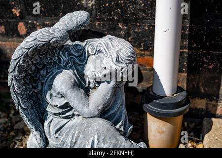 Fuoco vicino e selettivo di una statuetta dell'angelo in a. cortile posteriore privato con profondità di campo intenzionale poco profonda e. bokeh Foto Stock