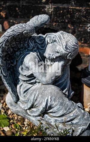 Fuoco vicino e selettivo di una statuetta dell'angelo in a. cortile posteriore privato con profondità di campo intenzionale poco profonda e. bokeh Foto Stock